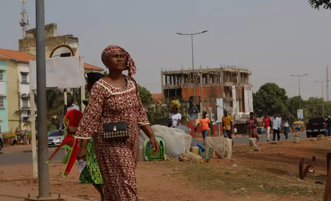 People walk on the street in Bissau, Guinea-Bissau, Wednesday, Nov. 26, 2025. (AP Photo/Darcicio Barbosa)