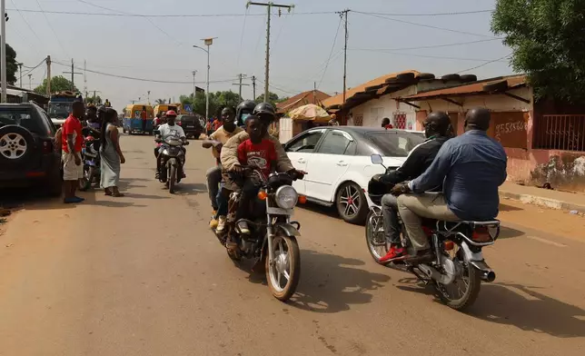People ride on motorcycle taxis on the street in Bissau, Guinea-Bissau, Wednesday, Nov. 26, 2025. (AP Photo/Darcicio Barbosa)