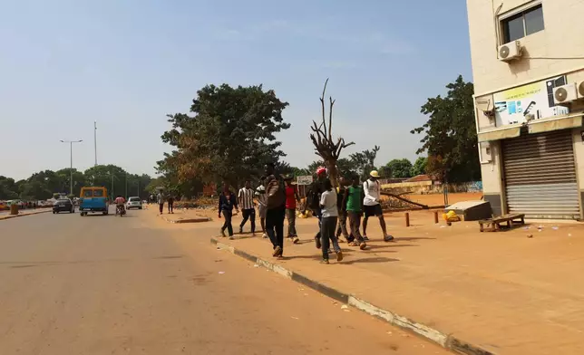 People walk on the street in Bissau, Guinea-Bissau, Wednesday, Nov. 26, 2025. (AP Photo/Darcicio Barbosa)