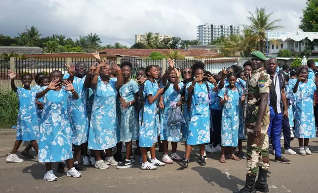 People cheer as the motorcade of France's President Emmanuel Macron and Gabon's President Brice Oligui Nguema drives past, in Libreville, Gabon, Monday, Nov. 24, 2025. (AP Photo/Thibault Camus)