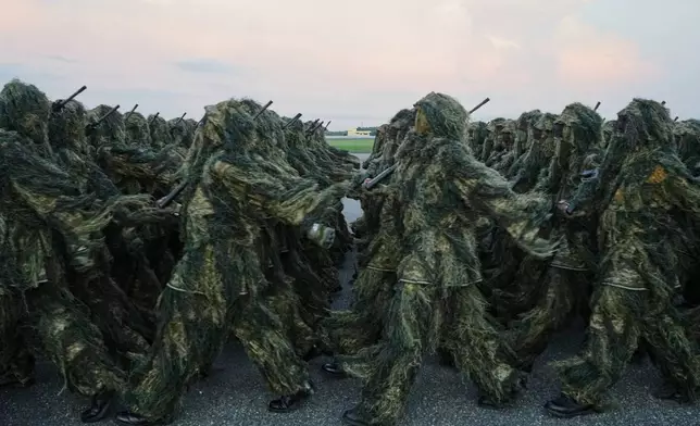 Gabon's army troops parade as French President Emmanuel Macron is greeted by Gabon's President Brice Oligui Nguema upon his arrival at the Leon-Mba International Airport in Libreville, Gabon, Sunday, Nov. 23, 2025. (AP Photo/Thibault Camus)