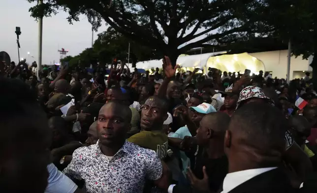 Supporters attend the arrival of France's President Emmanuel Macron at the Leon-Mba International Airport in Libreville, Gabon, Sunday, Nov. 23, 2025. (AP Photo/Thibault Camus)