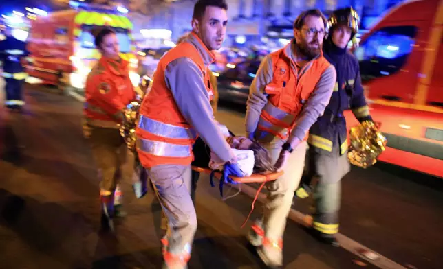 FILE - Medics evacuate a woman from the Bataclan concert hall after a shooting in Paris Nov. 13, 2015. (AP Photo/Thibault Camus, File)
