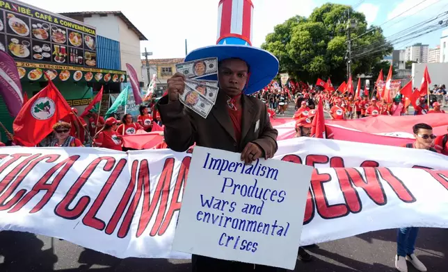 Flavio Pinto participates in a climate protest holding money with President Donald Trump's face on it during the COP30 U.N. Climate Summit, Saturday, Nov. 15, 2025, in Belem, Brazil. (AP Photo/Fernando Llano)