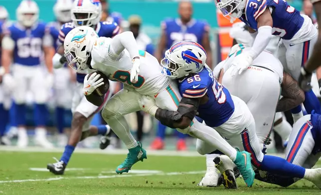 Miami Dolphins' De'Von Achane (28) is tackled by Buffalo Bills' Javon Solomon (56) during the first half of an NFL football game, Sunday, Nov. 9, 2025, in Miami Gardens, Fla. (AP Photo/Rebecca Blackwell)