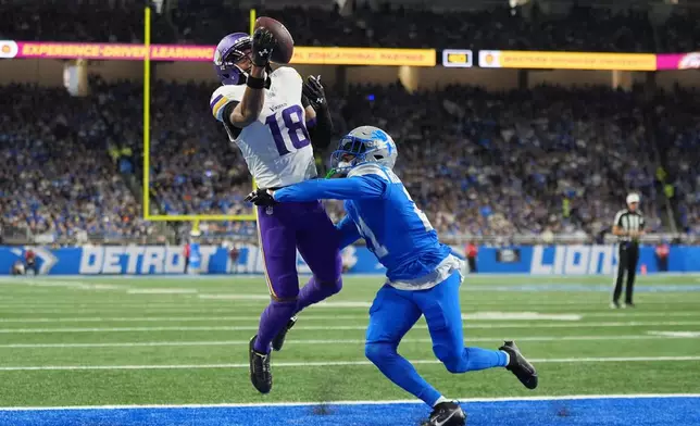 Minnesota Vikings wide receiver Justin Jefferson (18) catches a touchdown pass ahead of Detroit Lions cornerback Amik Robertson (21) during the first half of an NFL football game Sunday, Nov. 2, 2025, in Detroit. (AP Photo/Ryan Sun)