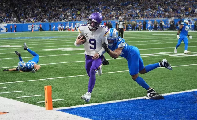 Minnesota Vikings quarterback J.J. McCarthy (9) scores a touchdown ahead of Detroit Lions safety Brian Branch (32) during the second half of an NFL football game Sunday, Nov. 2, 2025, in Detroit. (AP Photo/Paul Sancya)