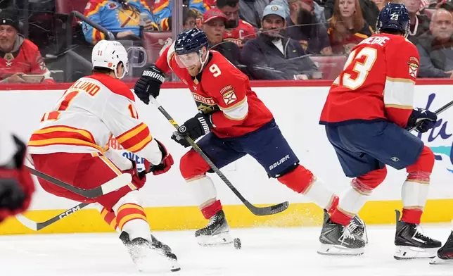 Florida Panthers center Sam Bennett (9) drives forward defended by Calgary Flames center Mikael Backlund (11) during the second period of an NHL hockey game, Friday, Nov. 28, 2025, in Sunrise, Fla. (AP Photo/Rebecca Blackwell)