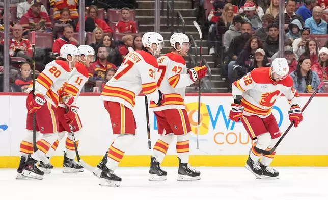 Calgary Flames defenseman MacKenzie Weegar (52) and teammates celebrate after he scored the team's second goal against the Florida Panthers during the first period of an NHL hockey game, Friday, Nov. 28, 2025, in Sunrise, Fla. (AP Photo/Rebecca Blackwell)
