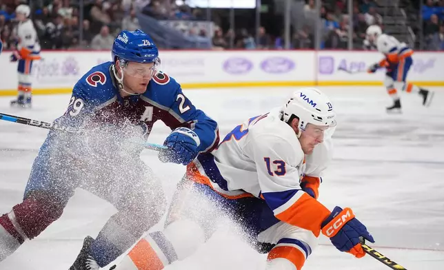 New York Islanders center Mathew Barzal, right, collects the puck as Colorado Avalanche center Nathan MacKinnon defends in the second period of an NHL hockey game Sunday, Nov. 16, 2025, in Denver. (AP Photo/David Zalubowski)