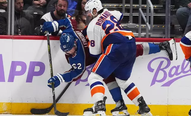 New York Islanders defenseman Alexander Romanov, front, pins Colorado Avalanche left wing Artturi Lehkonen to the boards in the second period of an NHL hockey game Sunday, Nov. 16, 2025, in Denver. (AP Photo/David Zalubowski)