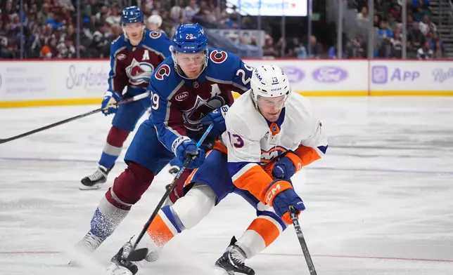 New York Islanders center Mathew Barzal, front, collects the puck as Colorado Avalanche center Nathan MacKinnon defends in the second period of an NHL hockey game Sunday, Nov. 16, 2025, in Denver. (AP Photo/David Zalubowski)