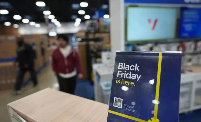 People pass a display as they walks among early Black Friday sale items at Best Buy Thursday, Nov. 20, 2025, in San Diego. (AP Photo/Gregory Bull)