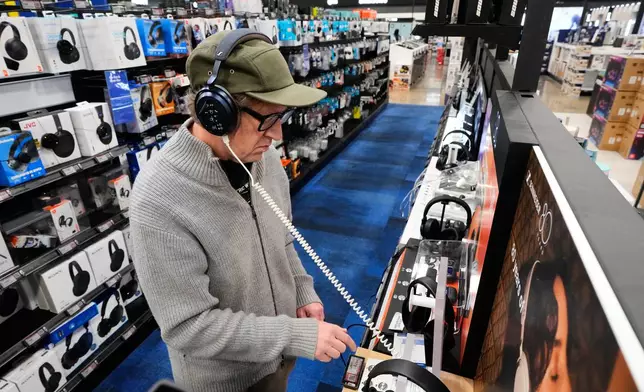 Chad Cook of Dallas, tries checks out a headphone unit as he shops at a Best Buy store, Wednesday, Nov. 26, 2025, in Dallas. (AP Photo/Tony Gutierrez)