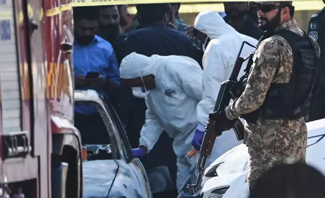 Pakistani investigators examine a damaged car at the site of a suicide bombing outside the gates of a district court, in Islamabad, Pakistan, Tuesday, Nov. 11, 2025. (AP Photo/Ahsan Shahzad)