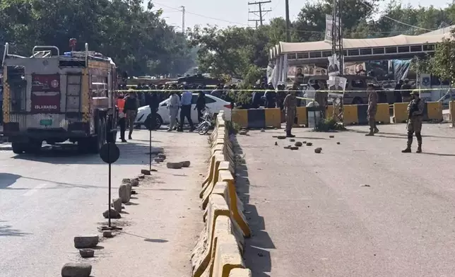 Pakistani security officials stand guard after a powerful car bomb exploded outside a district court in Islamabad, Pakistan, Tuesday, Nov. 11, 2025. (AP Photo/Mohammad Yousuf)