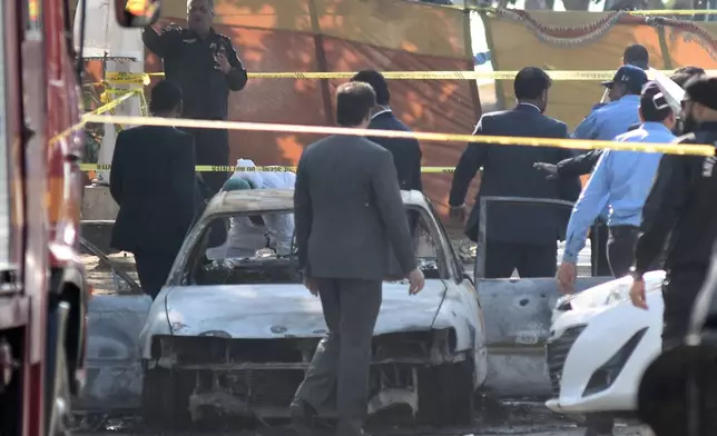 Pakistan's police officers and lawyers gather at the site following a suicide bombing outside the gates of a district court, in Islamabad, Pakistan, Tuesday, Nov. 11, 2025. (AP Photo/W.K. Yousufzai)