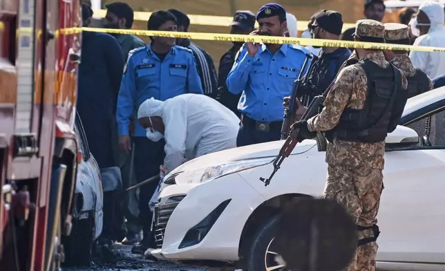Pakistani investigators examine a damage car at the site of a suicide bombing outside the gates of a district court, in Islamabad, Pakistan, Tuesday, Nov. 11, 2025. (AP Photo/Ahsan Shahzad)