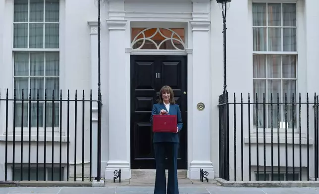 Britain's Chancellor of the Exchequer Rachel Reeves poses on the doorstep of 11 Downing Street with her ministerial red box before heading to the House of Commons to deliver her Budget speech in London, Wednesday, Nov. 26, 2025. (AP Photo/Kirsty Wigglesworth)
