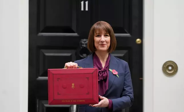FILE - Britain's Chancellor of the Exchequer, Rachel Reeves, holds up the traditional red ministerial box containing her budget speech, as she poses for the media outside No 11 Downing Street, before departing to the House of Commons to deliver the budget in London, Wednesday, Oct. 30, 2024. (AP Photo/Kirsty Wigglesworth, File)