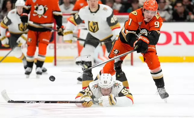 Vegas Golden Knights right wing Mitch Marner, below, and Anaheim Ducks center Leo Carlsson reach for the puck during the first period of an NHL hockey game Saturday, Nov. 22, 2025, in Anaheim, Calif. (AP Photo/Mark J. Terrill)