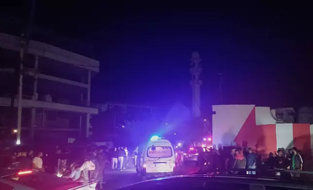 People gathering next of an ambulance as it enters the Ein el-Hilweh refugee camp in the southern port city of Sidon, Lebanon, Tuesday, Nov. 18, 2025. (AP Photo/Mohammed Zaatari)