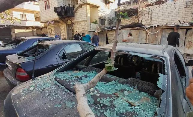 Palestinian people check cars that were damaged by an Israeli strike that hit on Tuesday night in the Ein el-Hilweh Palestinian refugee camp, in the southern port city of Sidon, Lebanon, Wednesday, Nov. 19, 2025. (AP Photo/Mohammed Zaatari)
