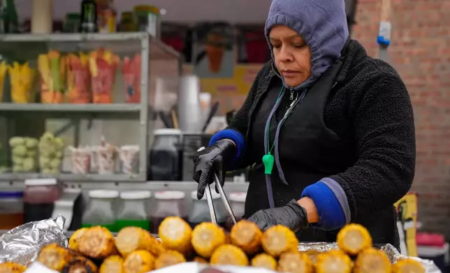 Ofelia Herrera, originally from Mexico, grills corn at her family's street food stand in Little Village, Nov. 8, 2025, in Chicago. (AP Photo/Erin Hooley)
