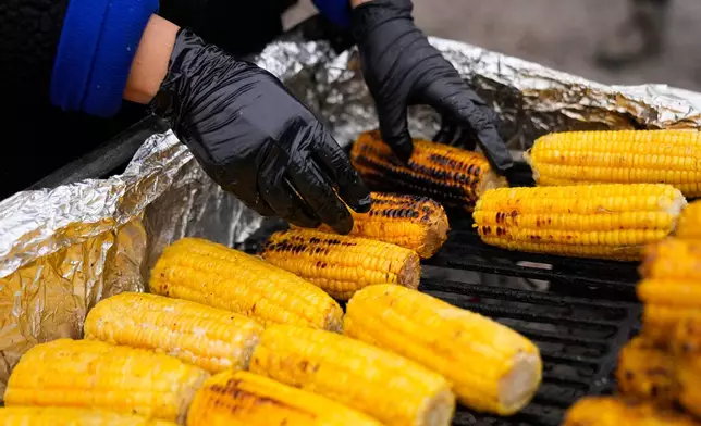 Ofelia Herrera, originally from Mexico, grills corn at her family's street food stand in Little Village, Nov. 8, 2025, in Chicago. (AP Photo/Erin Hooley)