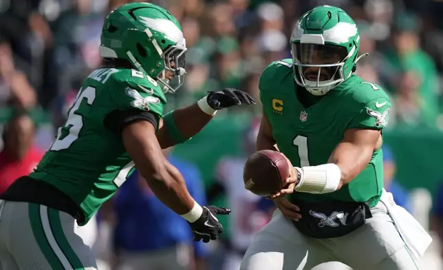 Philadelphia Eagles quarterback Jalen Hurts, right, hands off to Eagles running back Saquon Barkley (26) who runs for a touchdown during the first half of an NFL football game against the New York Giants on Sunday, Oct. 26, 2025, in Philadelphia. (AP Photo/Matt Slocum)