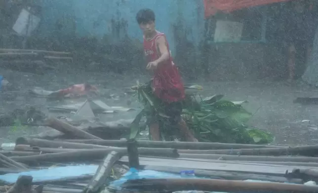 A resident cleans up debris during heavy rainfall in their coastal village, which was affected by Typhoon Fung-wong on Monday, Nov. 10, 2025, in Navotas, Philippines. (AP Photo/Aaron Favila)