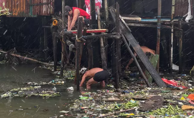 Residents fix their home during rain due to Typhoon Fung-wong along a coastal village on Monday, Nov. 10, 2025, in Navotas, Philippines. (AP Photo/Aaron Favila)