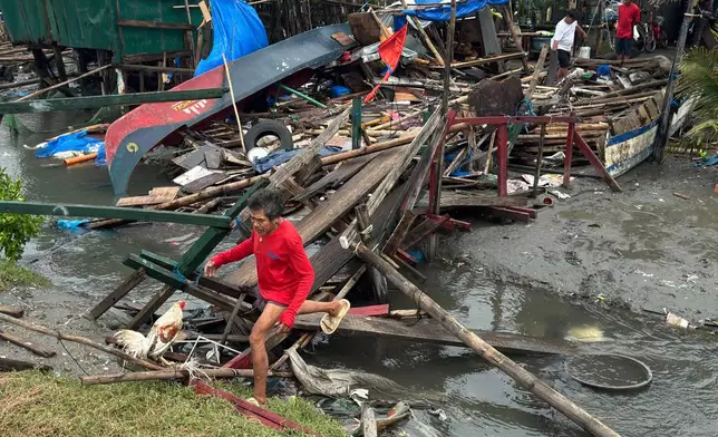 A man crosses a damaged bridge and house due to Typhoon Fung-wong along a coastal village on Monday, Nov. 10, 2025, in Navotas, Philippines. (AP Photo/Aaron Favila)