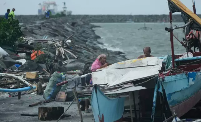 A woman and man secure their shelter as rain pours due to Typhoon Fung-wong on Monday, Nov. 10, 2025, in Manila, Philippines. (AP Photo/Aaron Favila)