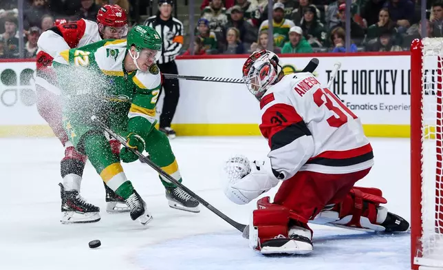 Minnesota Wild right wing Danila Yurov (22) and Carolina Hurricanes left wing Jordan Martinook (48) compete for the puck as goaltender Frederik Andersen (31) defends his net during the third period of an NHL hockey game Wednesday, Nov. 19, 2025, in St. Paul, Minn. (AP Photo/Matt Krohn)