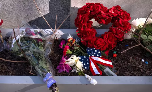 A small memorial of flags, flowers, other items are seen in a planter, Friday, Nov. 28, 2025, near the site where two National Guard members were shot in Washington. (AP Photo/Mark Schiefelbein)