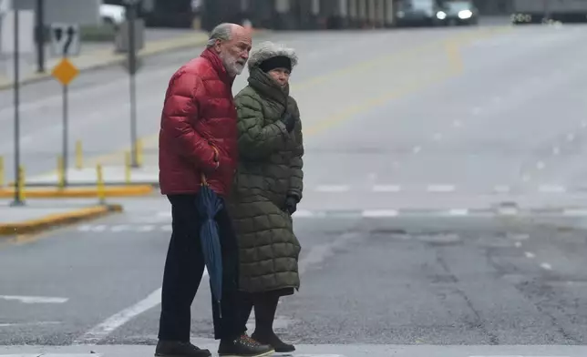 Pedestrians cross a street during a cold day in Chicago, Sunday, Nov. 9, 2025. (AP Photo/Nam Y. Huh)