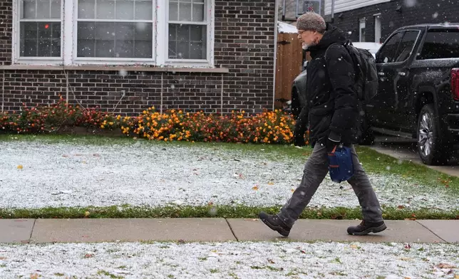 Pedestrian walks on the sidewalk during a snowy day in Skokie, Ill., Sunday, Nov. 9, 2025. (AP Photo/Nam Y. Huh)