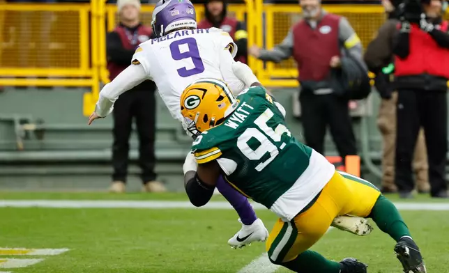 Minnesota Vikings quarterback J.J. McCarthy (9) is sacked by Green Bay Packers defensive tackle Devonte Wyatt (95) during the second half of an NFL football game Sunday, Nov. 23, 2025, in Green Bay, Wis. (AP Photo/Mike Roemer)