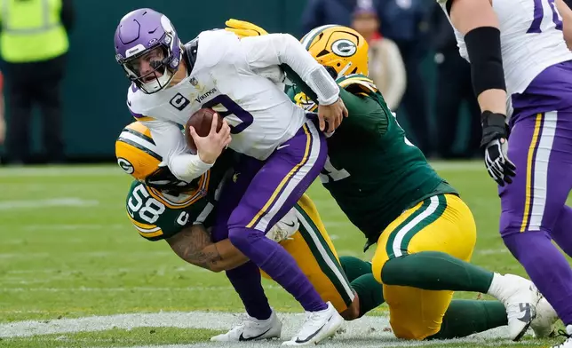 Minnesota Vikings quarterback J.J. McCarthy (9) is tackled by Green Bay Packers linebacker Isaiah McDuffie (58) and defensive tackle Warren Brinson (91) during the first half of an NFL football game Sunday, Nov. 23, 2025, in Green Bay, Wis. (AP Photo/Mike Roemer)