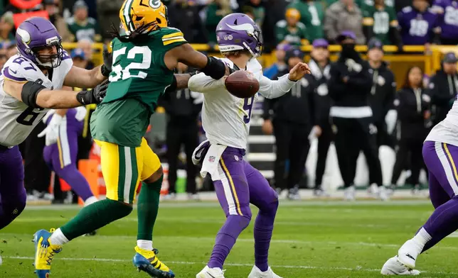 Minnesota Vikings quarterback J.J. McCarthy (9) looks to pass as Green Bay Packers defensive end Rashan Gary (52) tries to tackle during the second half of an NFL football game Sunday, Nov. 23, 2025, in Green Bay, Wis. (AP Photo/Mike Roemer)