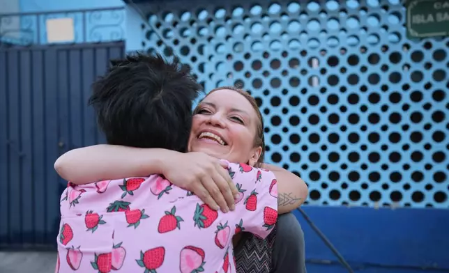 Diana Guzman, a driver with the feminist transportation collective AmorrAs, back to camera, hugs customer Ninfa Fuentes as she drops her off at her home in the State of Mexico, Thursday, Nov. 6, 2025. (AP Photo/Claudia Rosel)