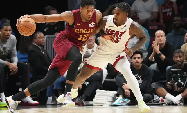 Cleveland Cavaliers forward De'Andre Hunter (12) dribbles the ball as Miami Heat guard Davion Mitchell (45) defends during the first half of an NBA basketball game Monday, Nov. 10, 2025, in Miami. (AP Photo/Marta Lavandier)