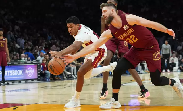 Miami Heat guard Dru Smith (12) and Cleveland Cavaliers forward Dean Wade (32) go after a loose ball during the first half of an NBA basketball game Monday, Nov. 10, 2025, in Miami. (AP Photo/Marta Lavandier)