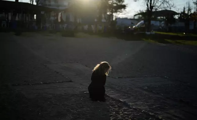Spanish Irati Aguirre, 26, makes a cross with stones as she waits for the arrival of Pope Leo XIV next to archaeological excavations of the ancient Byzantine-era Christian Saint Neophytos Basilica, in Iznik, Turkey, Friday, Nov. 28, 2025. (AP Photo/Khalil Hamra)