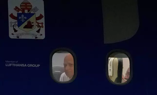 Pope Leo XIV peers from a window on board his papal plane bound to Istanbul, at Esenboga International Airport in Ankara, Turkey, Thursday, Nov. 27, 2025, during the first of his six-day trip to Turkey and Lebanon. (AP Photo/Khalil Hamra)