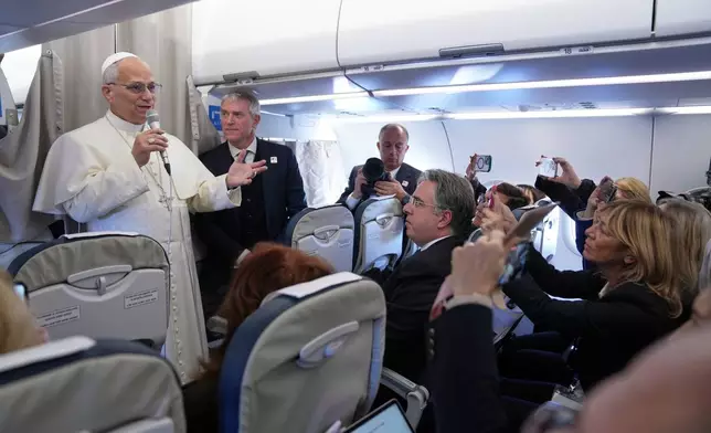 Pope Leo XIV greets reporters aboard a flight on his way to Ankara, Turkey, for a six-day trip to Turkey and Lebanon, Thursday, Nov. 27, 2025. (AP Photo/Domenico Stinellis, Pool)