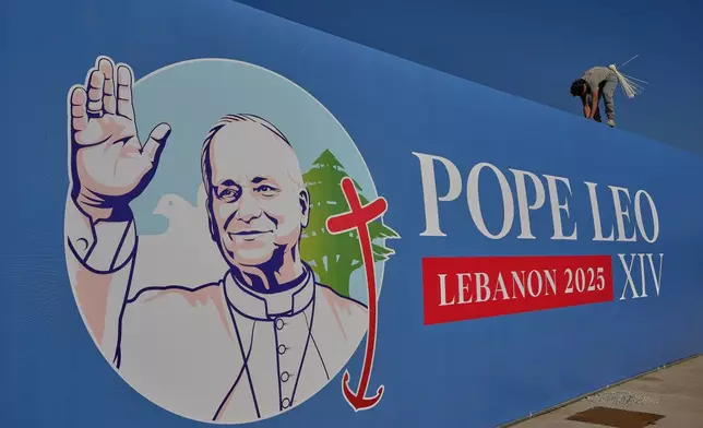 A worker sets a billboard displays an image of Pope Leo XIV in preparation of the area where he will holds a Holy mass during his visit to Lebanon, at the waterfront of downtown Beirut, Thursday, Nov. 27, 2025. (AP Photo/Hussein Malla)