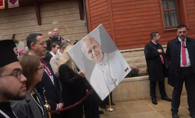 Valerena Yashou holds her painting of the Pope Leo XIV as the crowd wait for him to leave after attending the Doxology with Ecumenical Patriarch Bartholomew I, the spiritual leader of the world's Eastern Orthodox Christians, at the Patriarchal Church of Saint George, in Istanbul, Turkey, Saturday, Nov. 29, 2025. (AP Photo/Francisco Seco)
