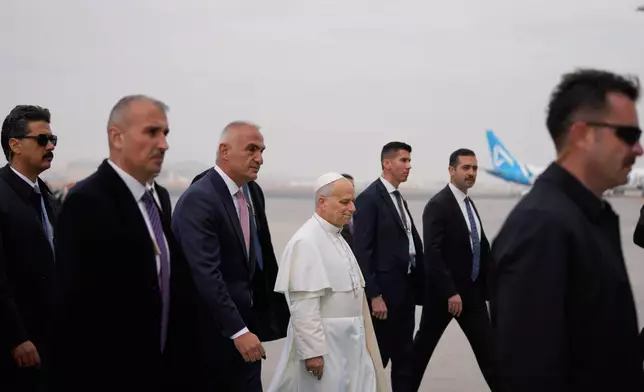 Pope Leo XIV is escorted by security members upon his arrival at Esenboga International Airport in Ankara, Turkey, Thursday, Nov. 27, 2025, marking the beginning of his first foreign trip. (AP Photo/Khalil Hamra)